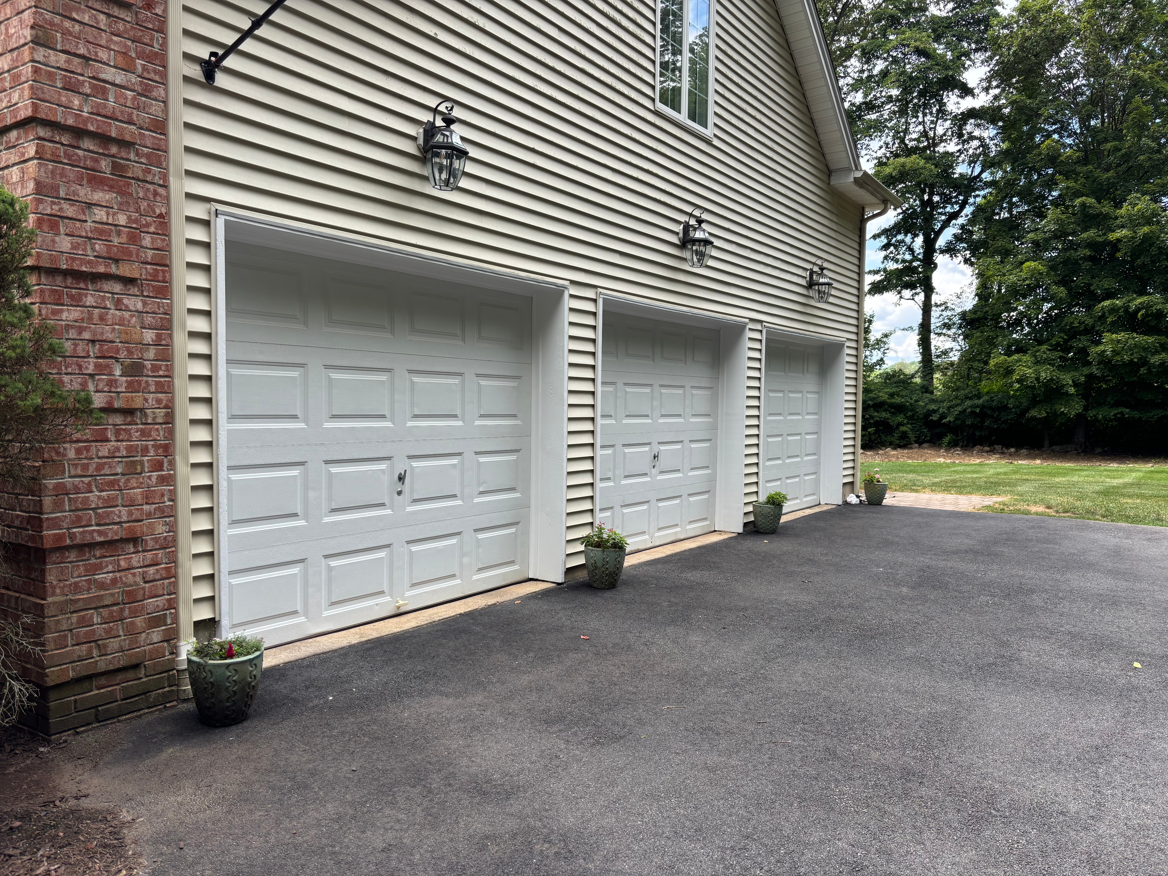 Professionally painted home exterior with brick accents and white garage doors